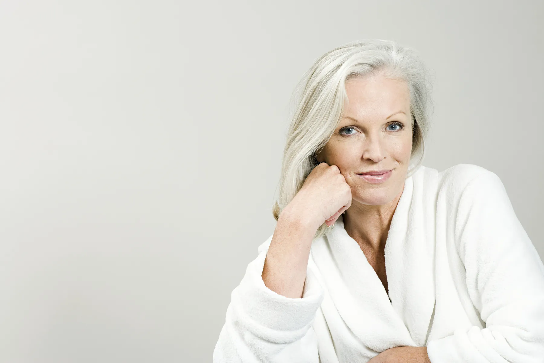 A woman in white robe posing serenely indoors