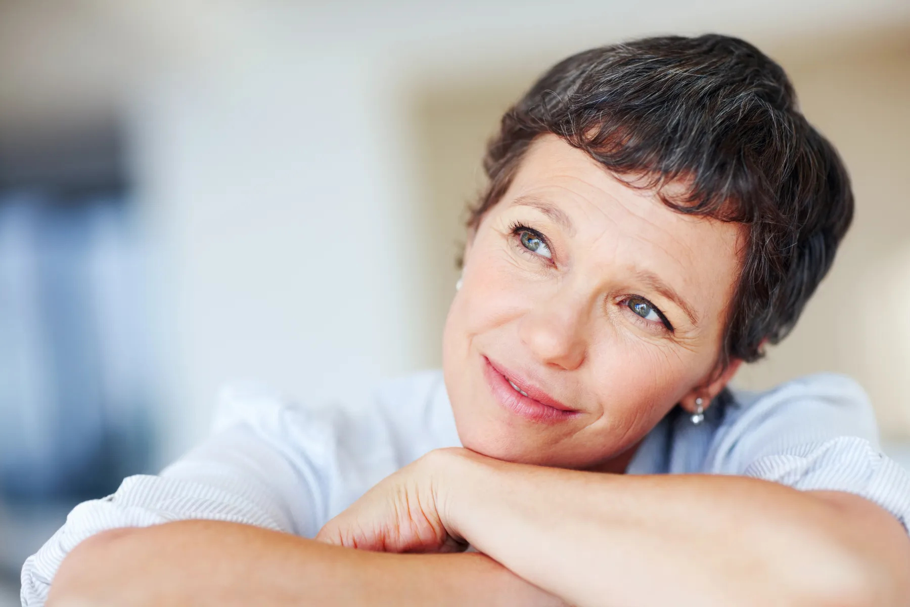A woman relaxing indoors daydreaming and smiling