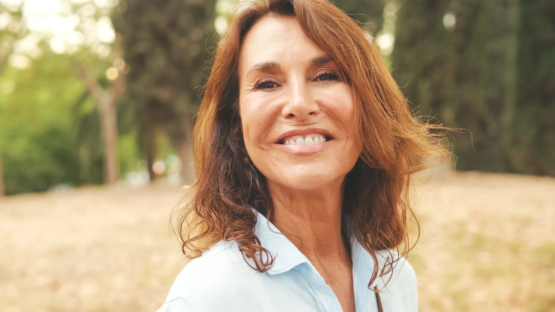 A woman smiling beautifully in park on a summer day