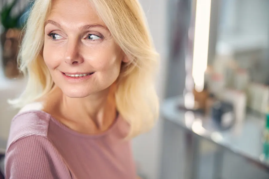 A woman with blond hair smiling in room
