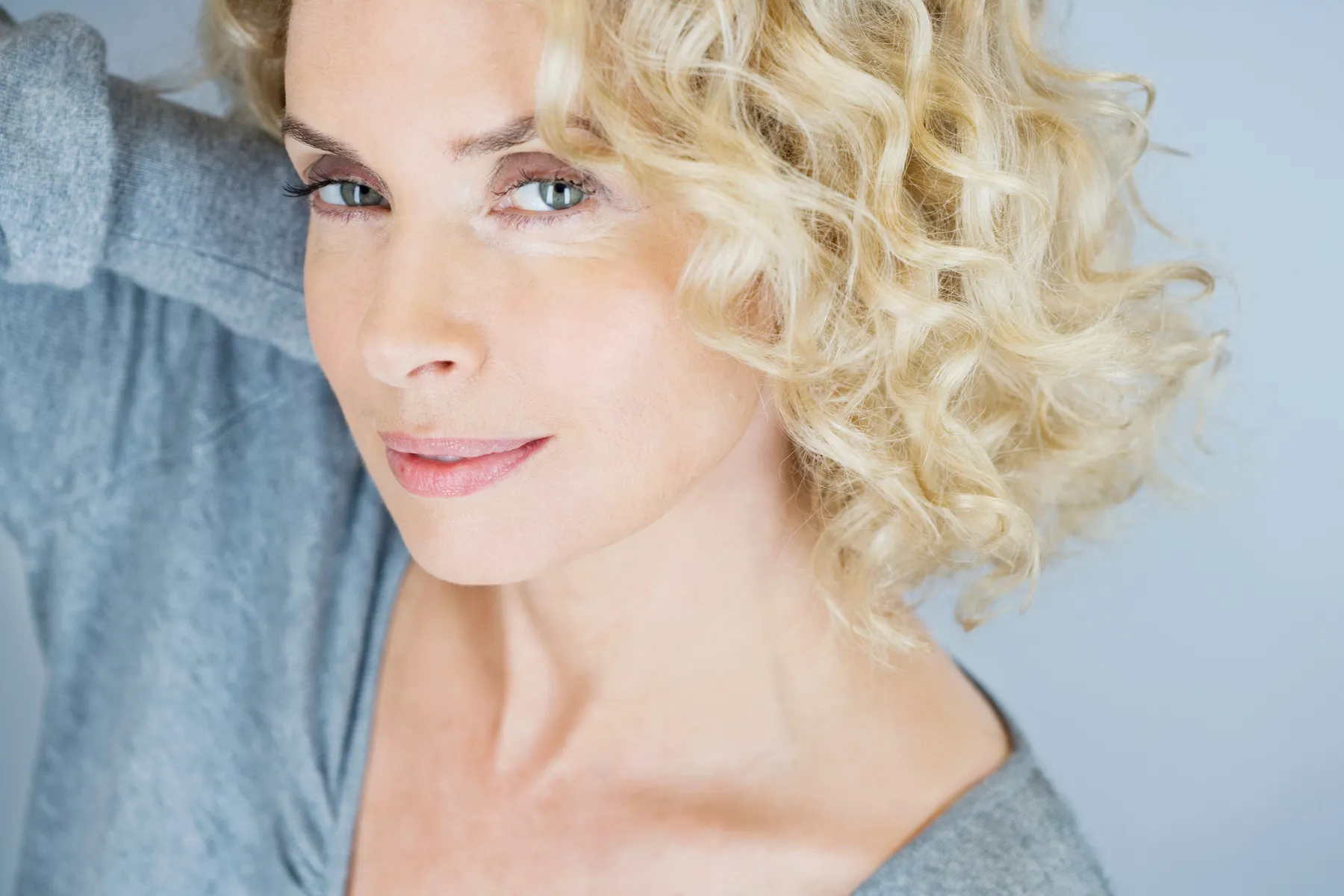 A woman with blonde curly hair posing in studio