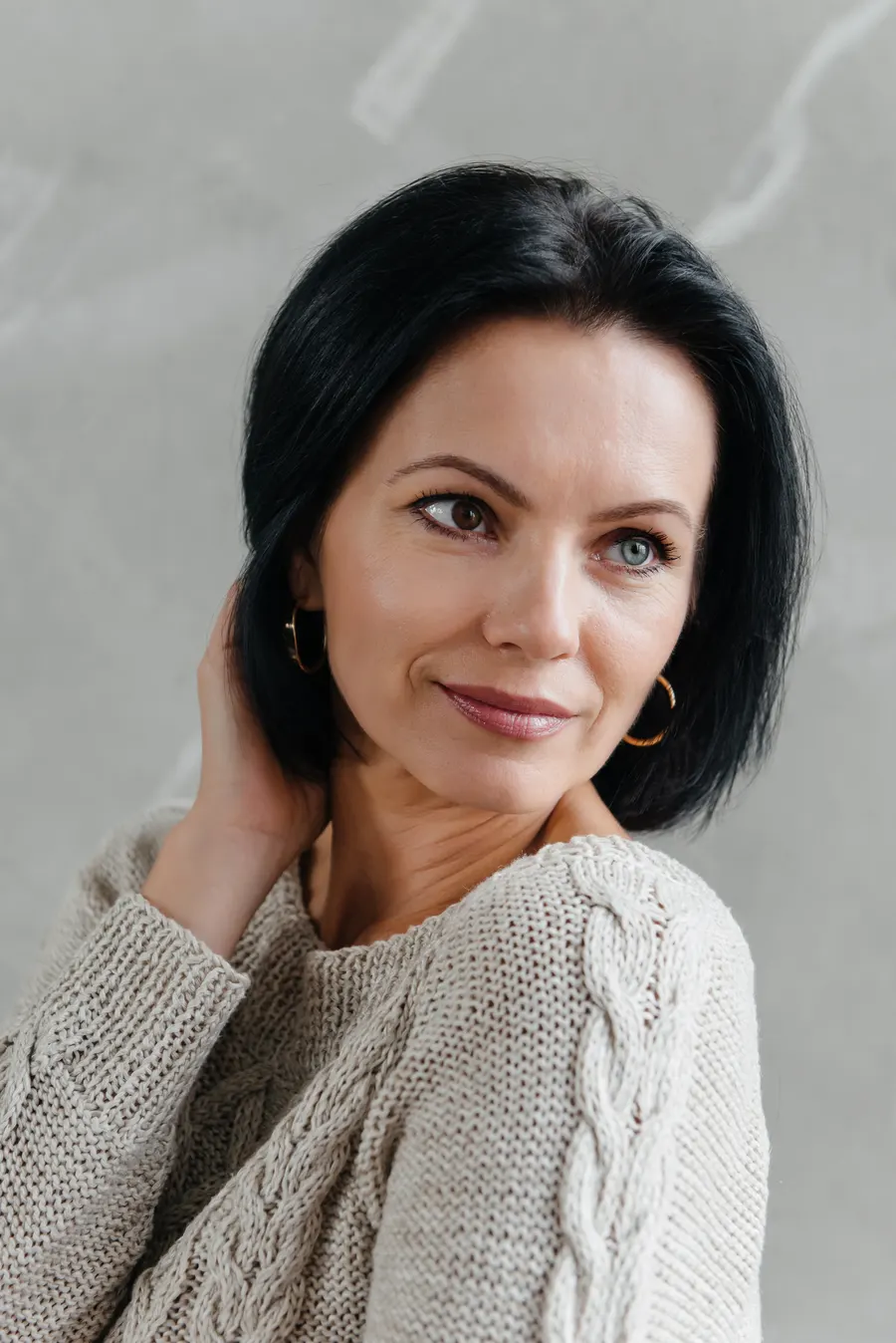 A woman with short black hair in neutral tones