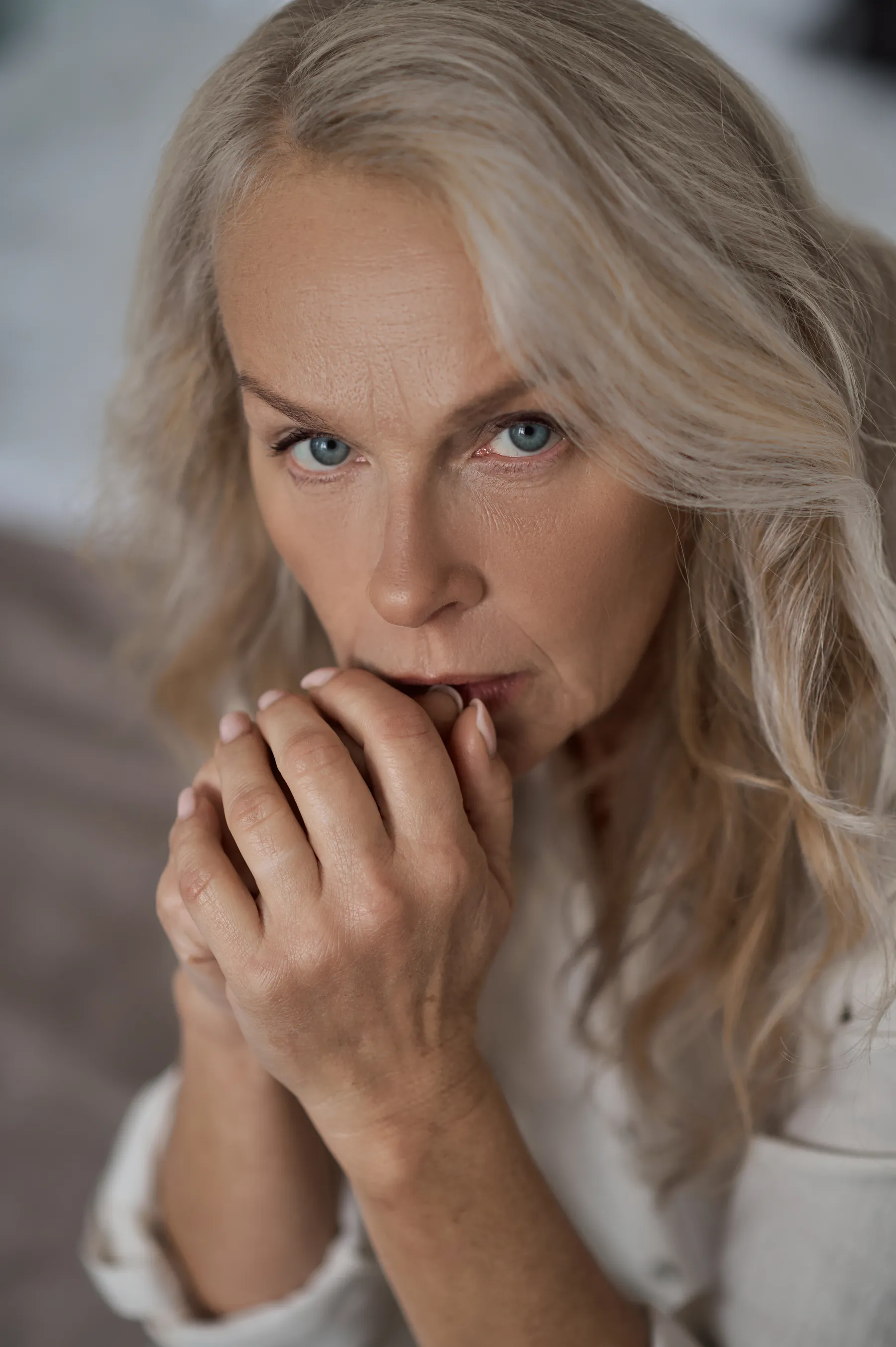 A worried woman with hands to mouth indoors